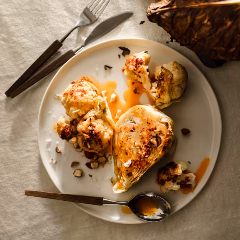 Geröstetes Kohlgemüse mit geräuchertem Paprika auf einem mit Tischtuch gedeckten Tisch und Besteck