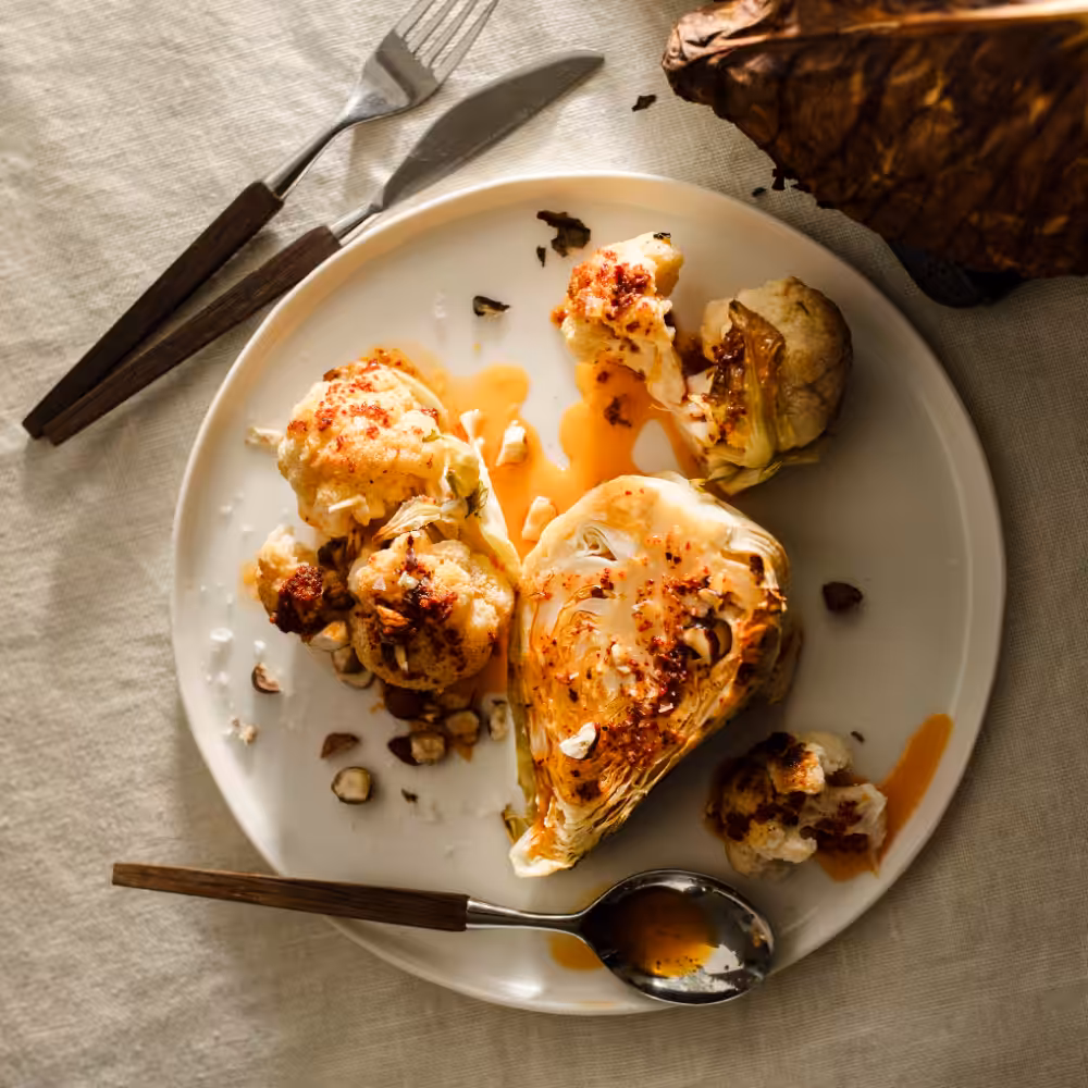 Geröstetes Kohlgemüse mit geräuchertem Paprika auf einem mit Tischtuch gedeckten Tisch und Besteck