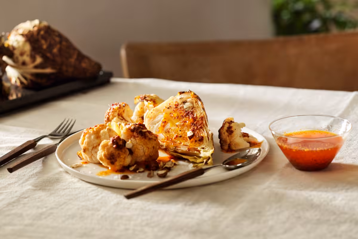 Geröstetes Kohlgemüse mit geräuchertem Paprika auf einem mit Tischtuch gedeckten Tisch und Besteck