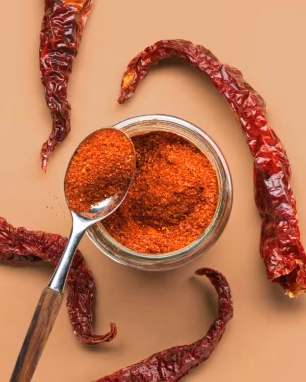 Ein Blick von oben in ein geöffnetes Bio Glas Räucher Paprika, umgeben von getrockneten Paprikaschoten